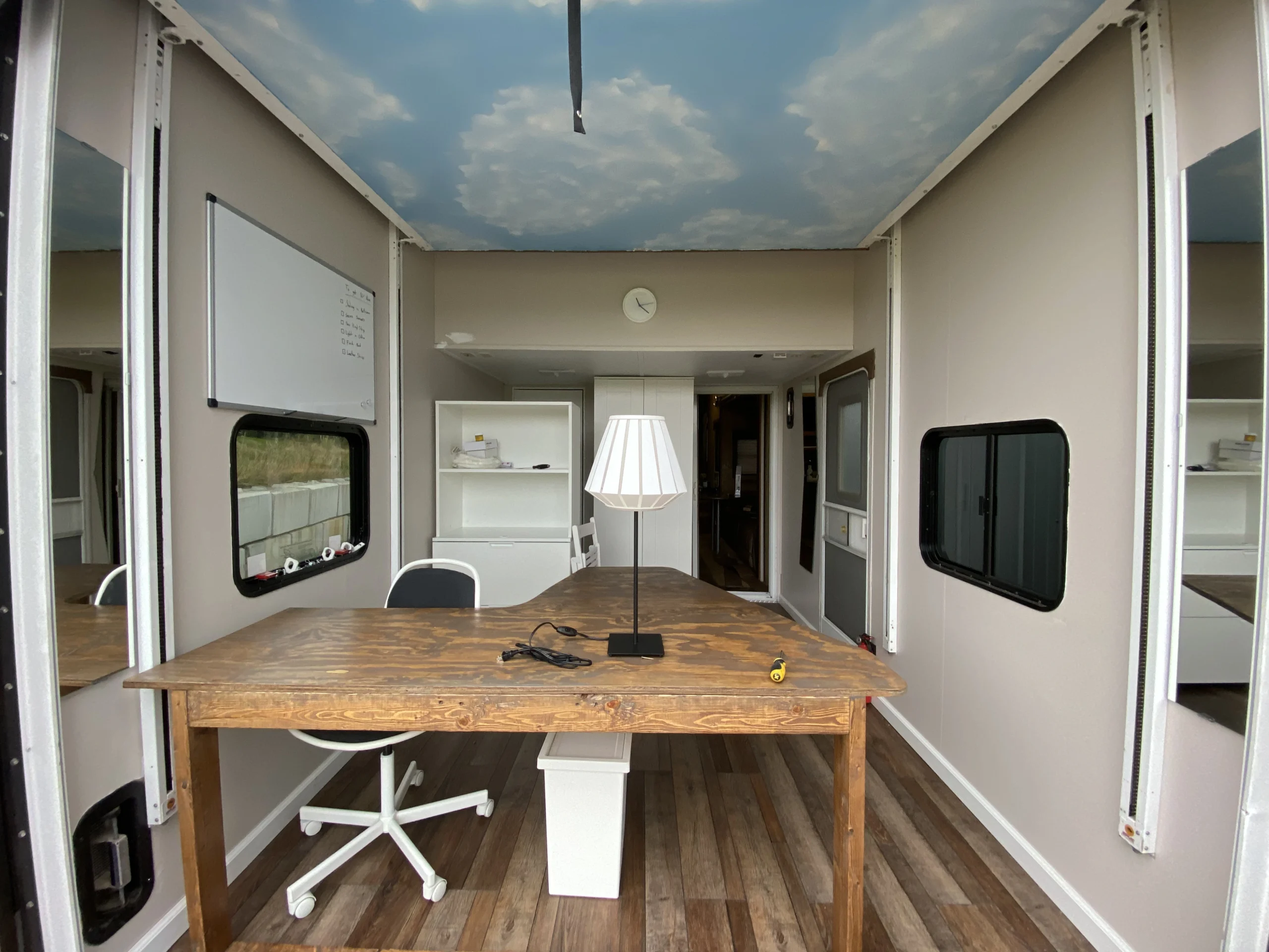 Clean, custom wooden desk workspace inside a converted mobile office trailer.