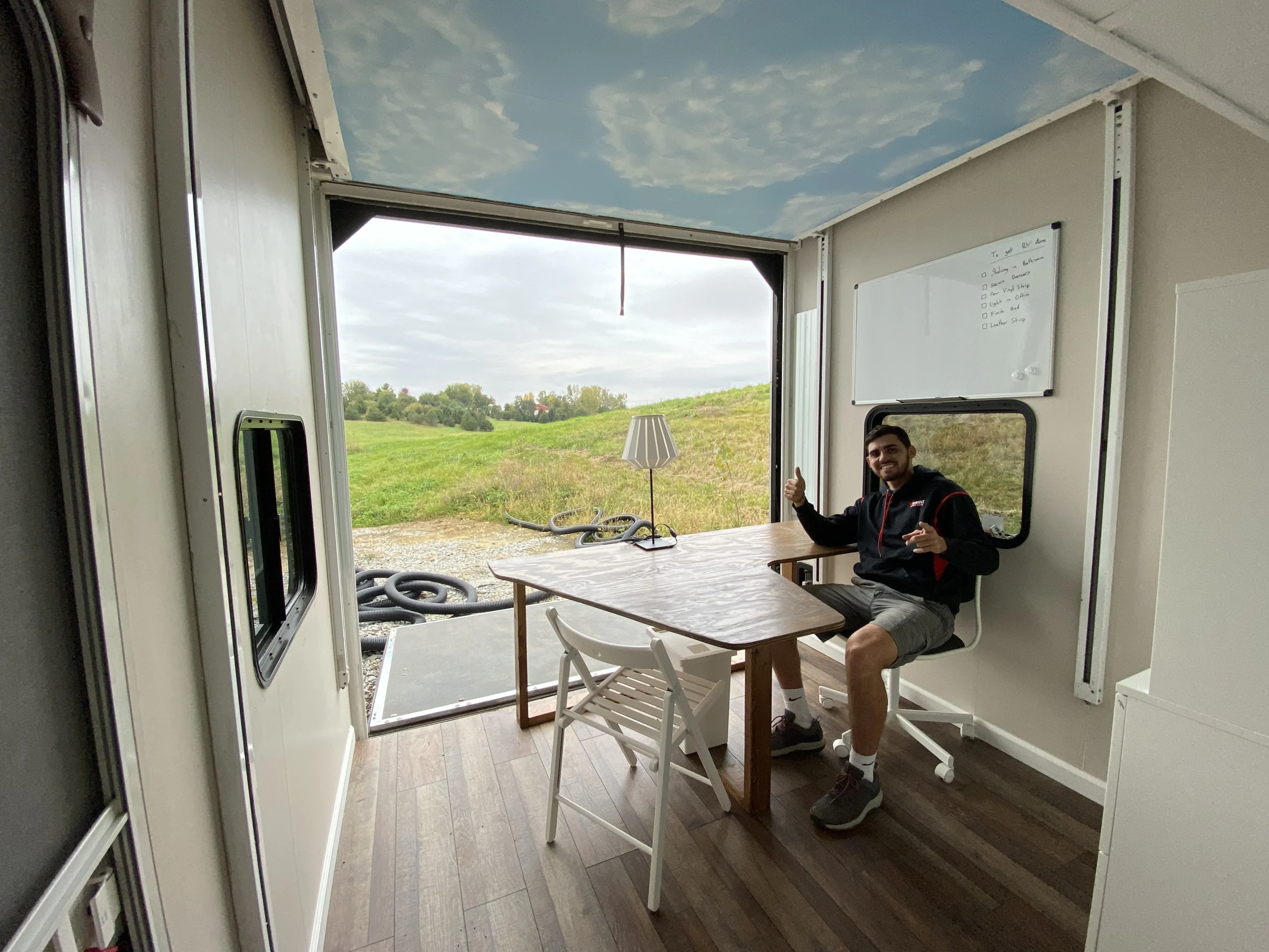 Team member giving a thumbs-up at a wooden desk inside a custom mobile office trailer.