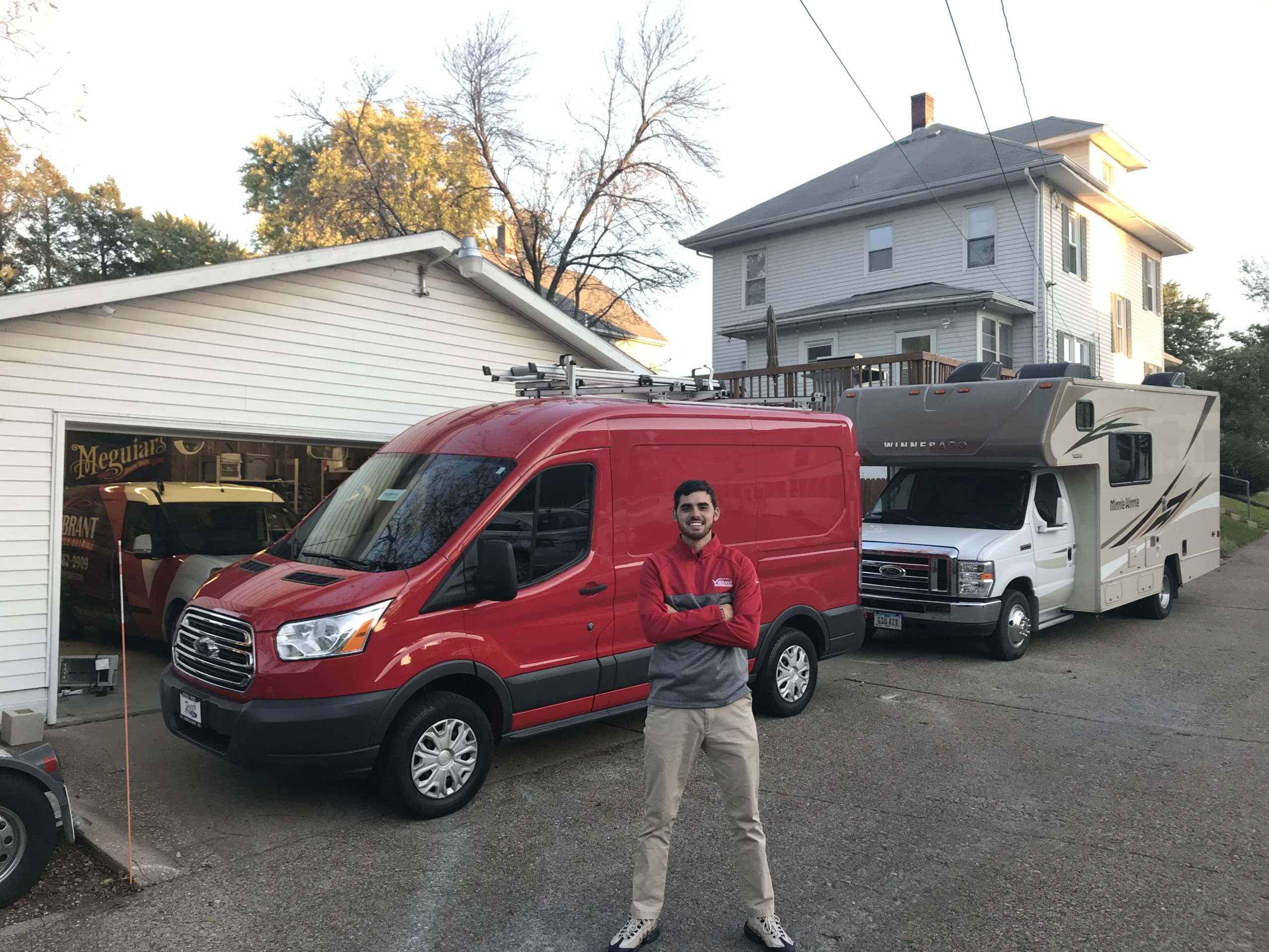 Mobile detailing professional standing proudly in front of a red service van and an RV.